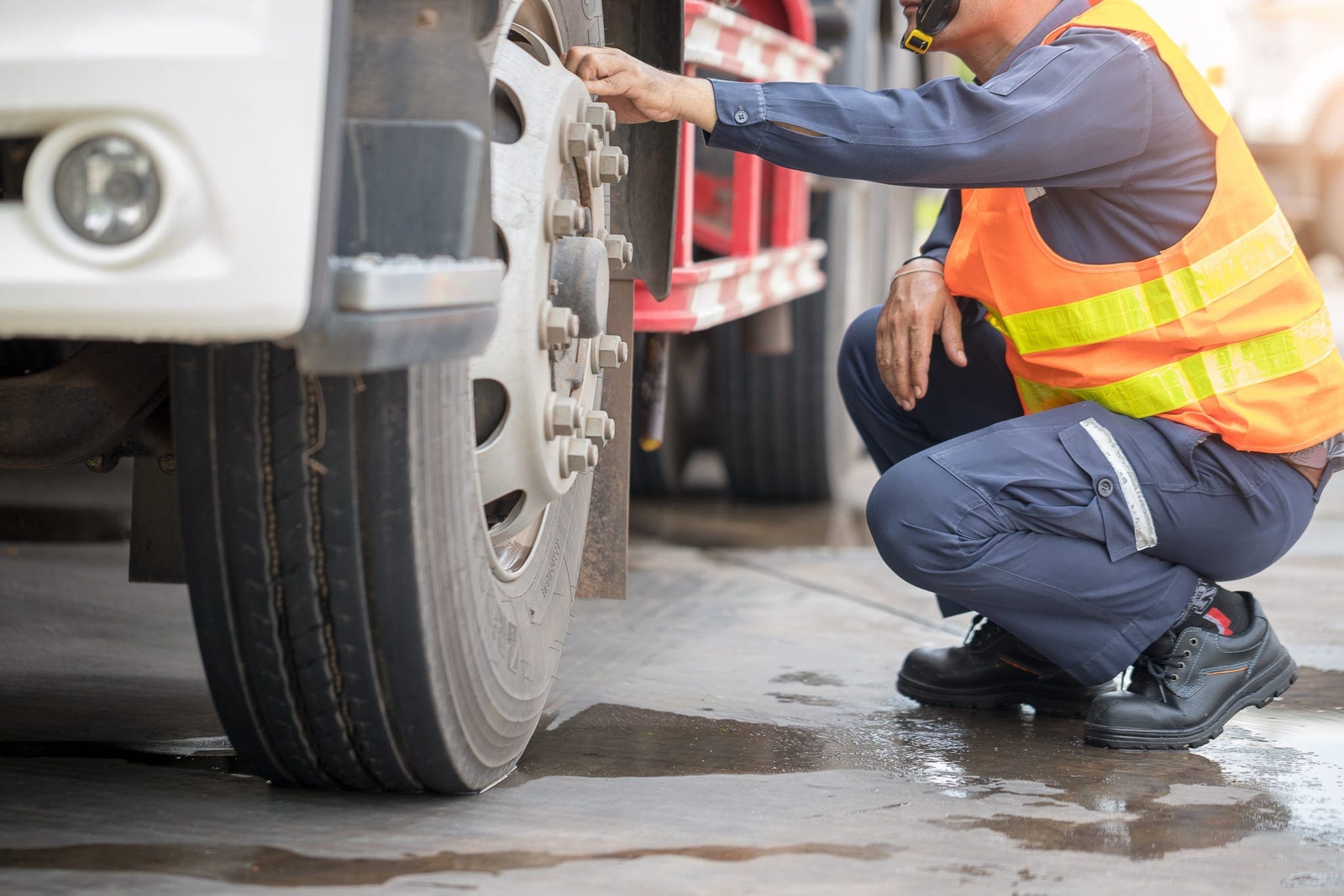 worker preforming a pre-trip inspection on a truck