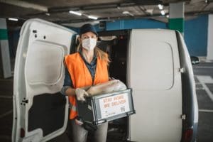 Courier in protective mask and medical gloves delivers items